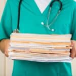 Close-up of a Nurse with Stack of Documents / Files